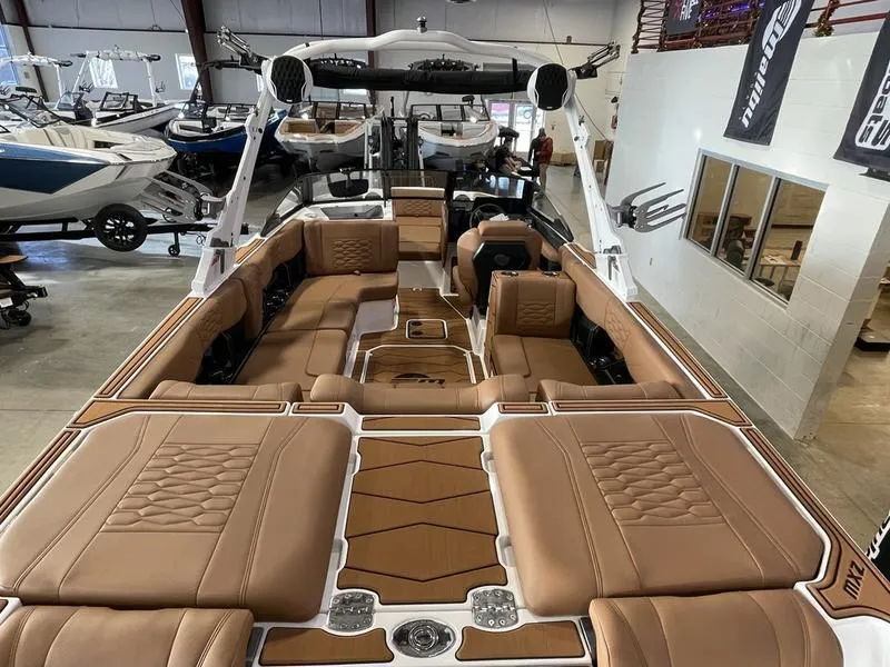 Slide: The Image of 2025 Malibu 24 MXZ boat interior with luxurious tan seating in showroom. - 10