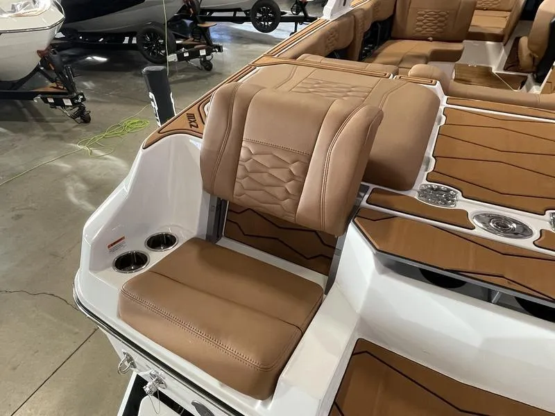 Slide: The Image of 2025 Malibu 24 MXZ boat interior with tan leather seating and cup holders. - 11