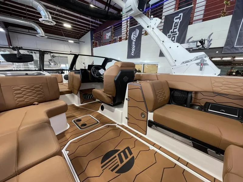 Slide: The Image of 2025 Malibu 24 MXZ boat interior with luxurious brown seating and modern design. - 15