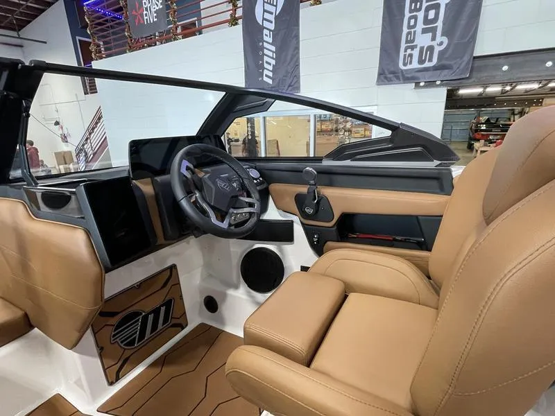 Slide: The Image of 2025 Malibu 24 MXZ boat interior with tan leather seats and modern dashboard. - 16