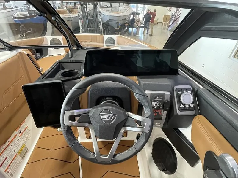 Slide: The Image of 2025 Malibu 24 MXZ boat dashboard with modern steering wheel and digital displays. - 18