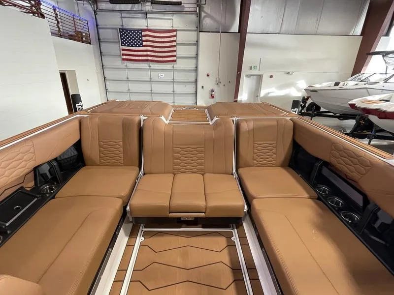 Slide: The Image of 2025 Malibu 24 MXZ boat interior with tan leather seating in a showroom. - 20