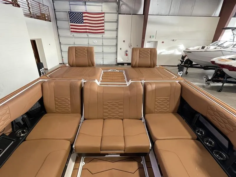 Slide: The Image of 2025 Malibu 24 MXZ boat interior with tan leather seating in a showroom. - 22
