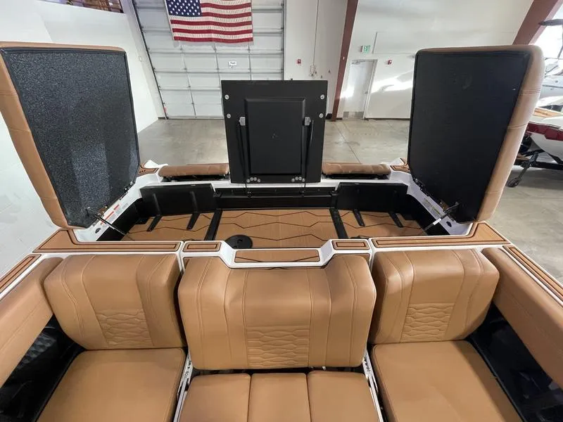 Slide: The Image of 2025 Malibu 24 MXZ boat interior with tan leather seats and open storage compartments. - 27