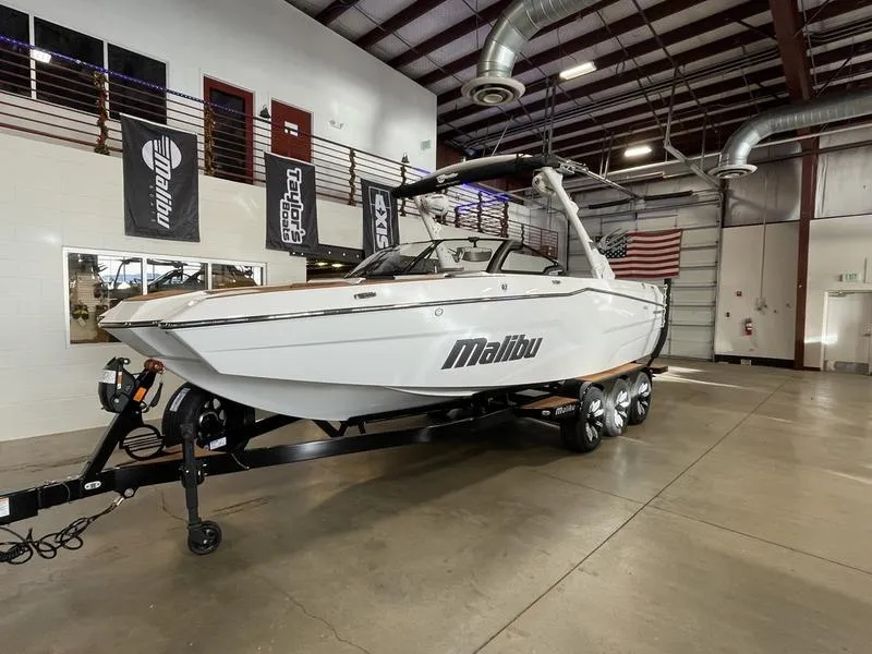 Slide: The Image of 2025 Malibu 24 MXZ boat on trailer in showroom, featuring sleek design and modern amenities. - 3