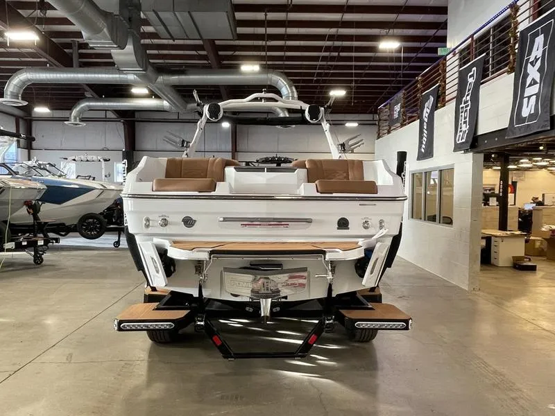Slide: The Image of 2025 Malibu 24 MXZ boat in showroom, rear view with seating and swim platform. - 8