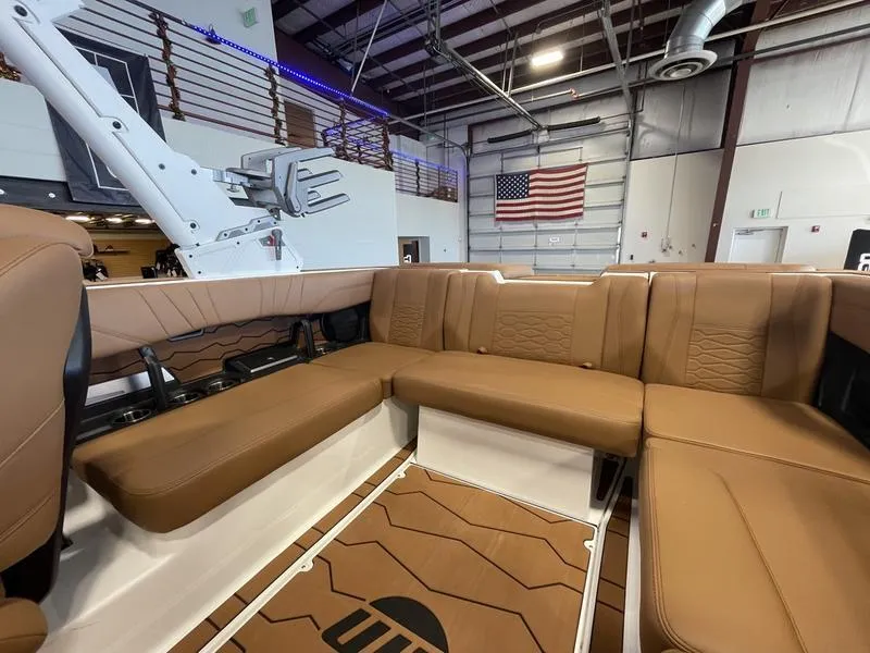 Slide: The Image of 2025 Malibu 22 MXZ boat interior with tan seating in a showroom. - 15