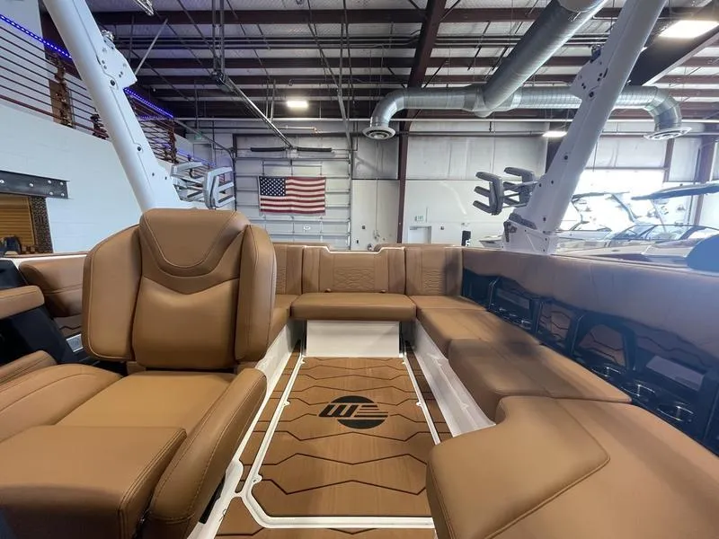 Slide: The Image of 2025 Malibu 22 MXZ boat interior with tan leather seating in a showroom. - 20