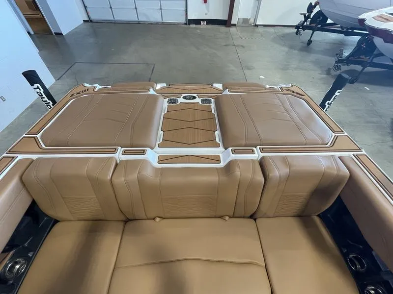 Slide: The Image of 2025 Malibu 22 MXZ boat interior with tan leather seating in a garage setting. - 23