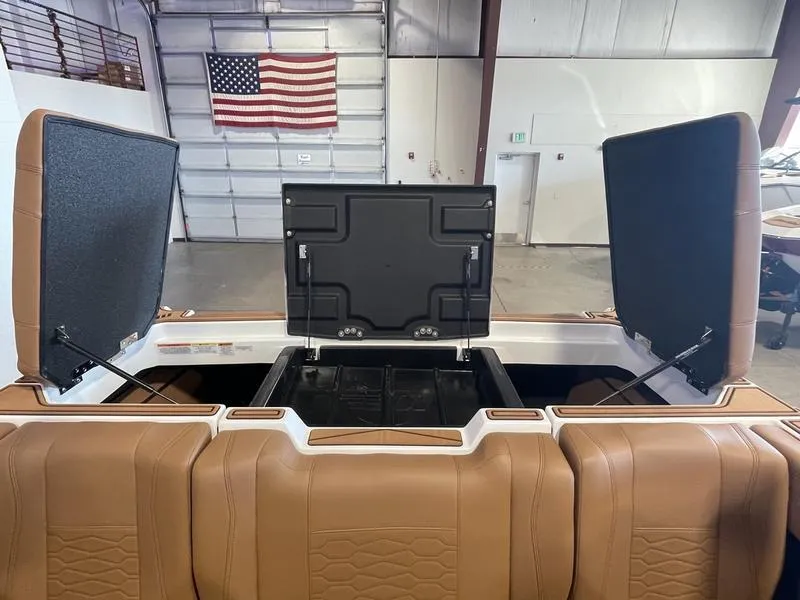 Slide: The Image of 2025 Malibu 22 MXZ boat interior with open storage compartments in a warehouse setting. - 25