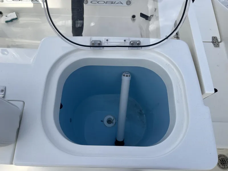 Slide: The Image of Livewell on 2025 Cobia 240 CC boat, open lid, white and blue interior. - 28