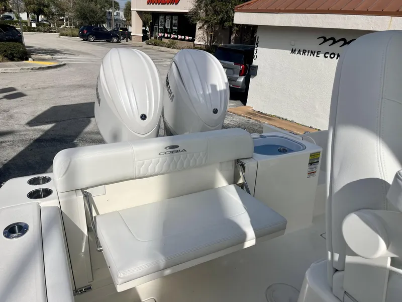 Slide: The Image of 2025 Cobia 240 CC boat with dual Yamaha engines, white seating, and cup holders. - 31