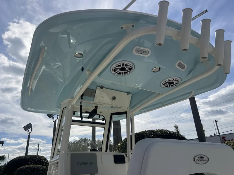 Slide: The Image of 2025 Cobia 240 CC boat with blue T-top and rod holders under a cloudy sky. - 32