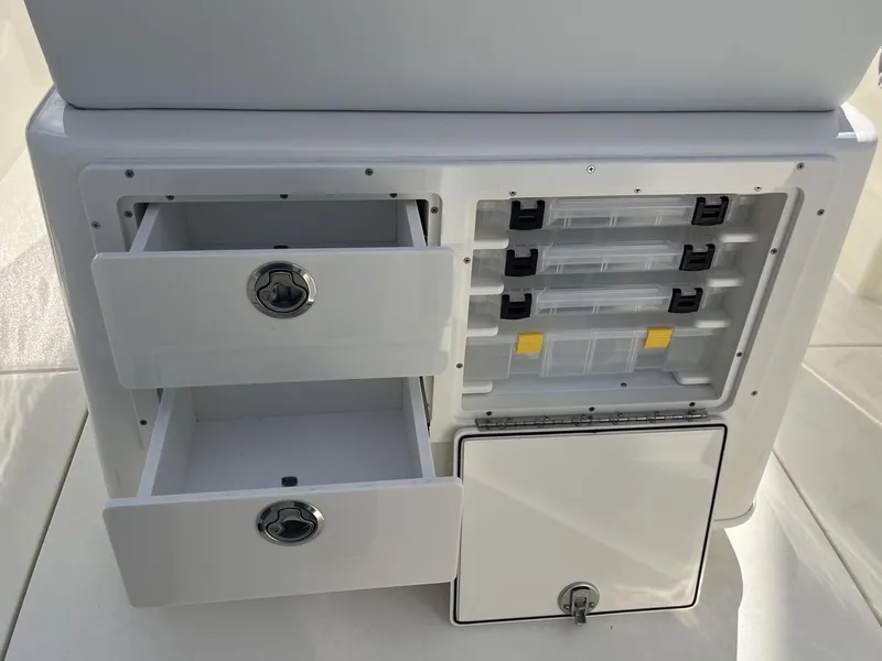 Slide: The Image of 2025 Cobia 240 CC boat storage compartments with drawers and tackle boxes. - 34