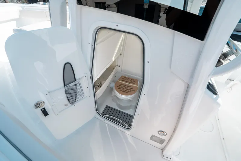 Slide: The Image of 2025 Sea Hunt GAMEFISH 27 CB boat interior with open door revealing compact restroom. - 31