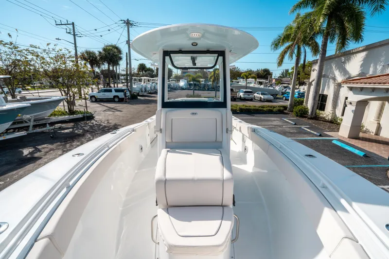 Slide: The Image of 2025 Sea Hunt GAMEFISH 27 CB boat, sleek design, parked outdoors under clear blue sky. - 37