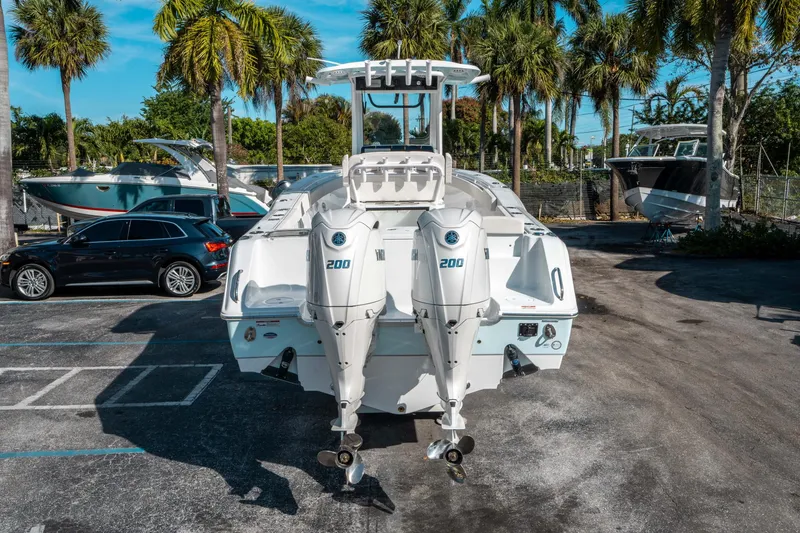 Slide: The Image of 2025 Sea Hunt GAMEFISH 27 CB boat with twin Yamaha 200 engines, parked under palm trees. - 3