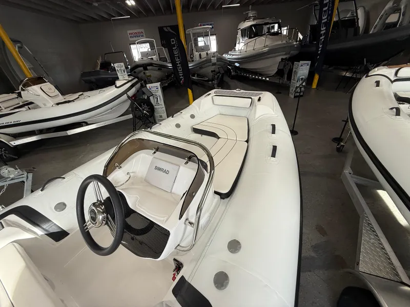 Slide: The Image of 2025 Walker Bay Generation 450 DLX boat in showroom, featuring sleek white design and modern interior. - 10