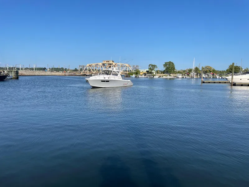 Slide: The Image of 2019 Pursuit OS 355 Offshore boat on calm water near a marina. - 3