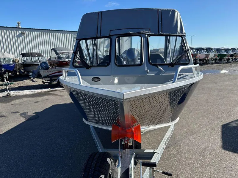 Slide: The Image of 2025 Hewescraft 180 Sportsman boat, front view, parked outdoors on a sunny day. - 2
