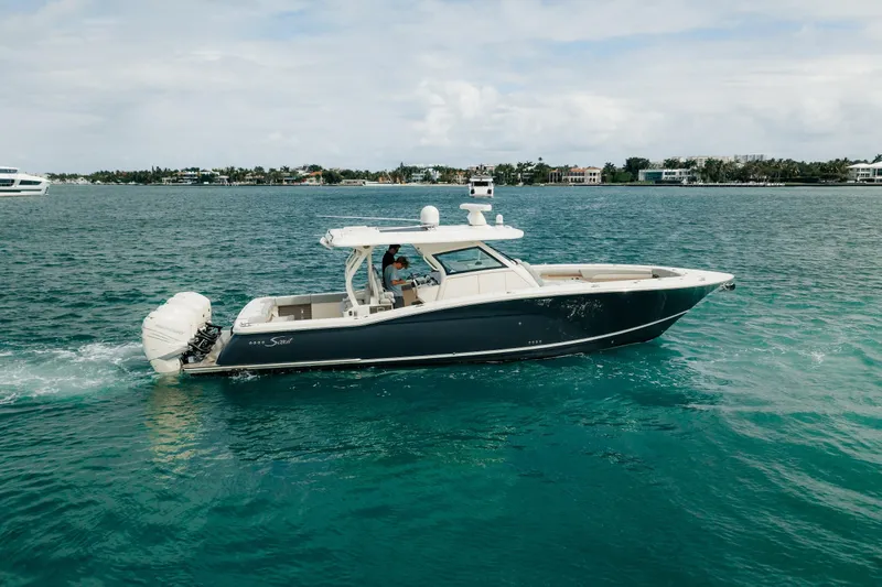 The Image of 2021 Scout 380 LXF boat cruising on clear blue water. - 0