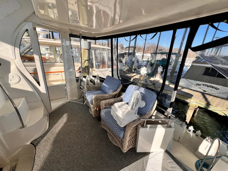 Slide: The Image of Interior of 2005 Carver 444 Cockpit Motor Yacht with wicker chairs and marina view. - 12