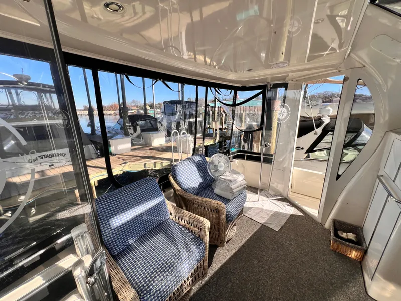 Slide: The Image of Interior of 2005 Carver 444 Cockpit Motor Yacht with wicker chairs and marina view. - 13