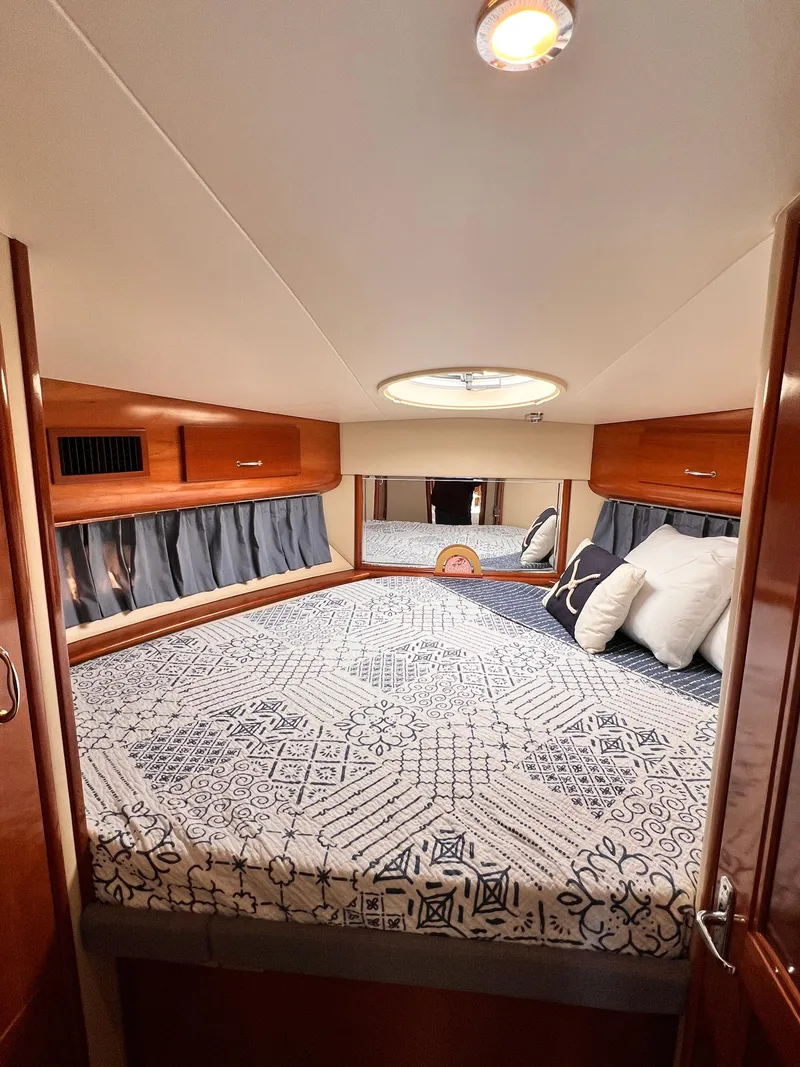 Slide: The Image of Interior of 2005 Carver 444 Cockpit Motor Yacht bedroom with patterned bedding and wooden accents. - 37