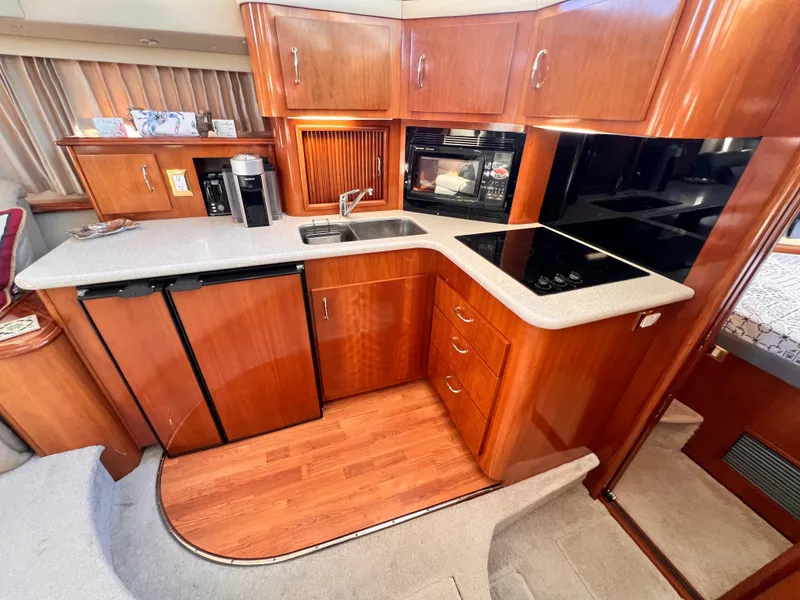 Slide: The Image of 2005 Carver 444 Cockpit Motor Yacht kitchen with wood cabinetry, sink, stove, and appliances. - 44
