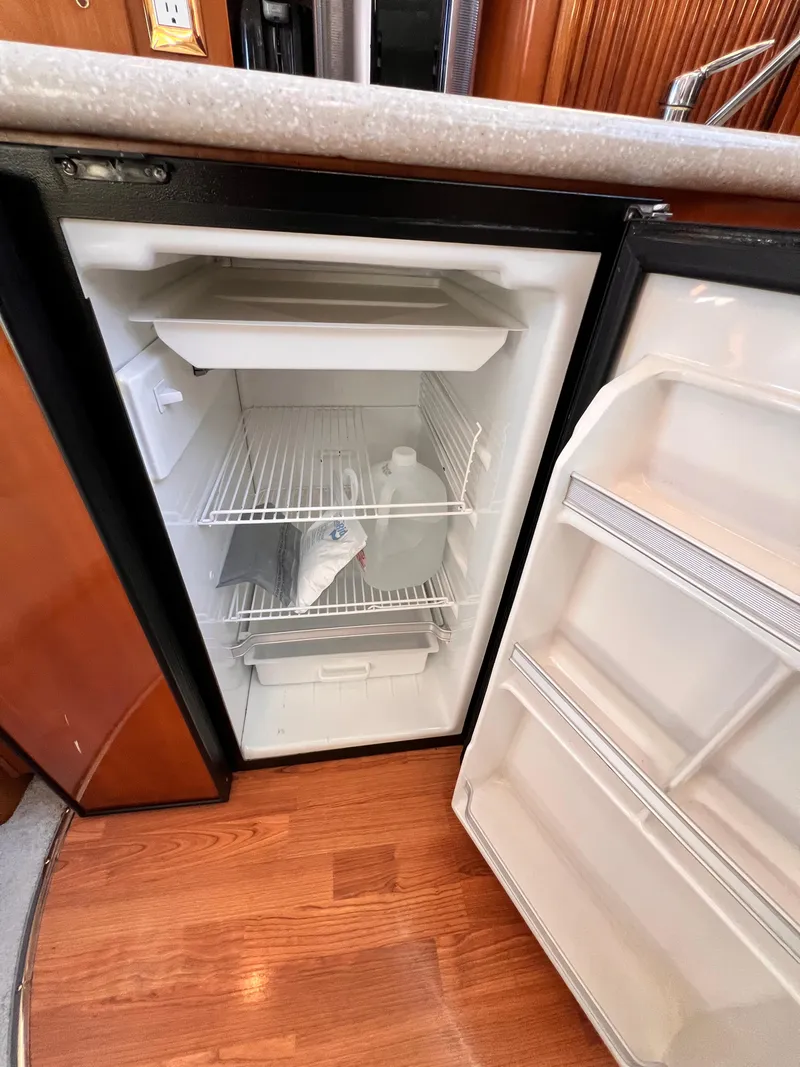 Slide: The Image of Open fridge inside 2005 Carver 444 Cockpit Motor Yacht, showing interior shelves and items. - 46