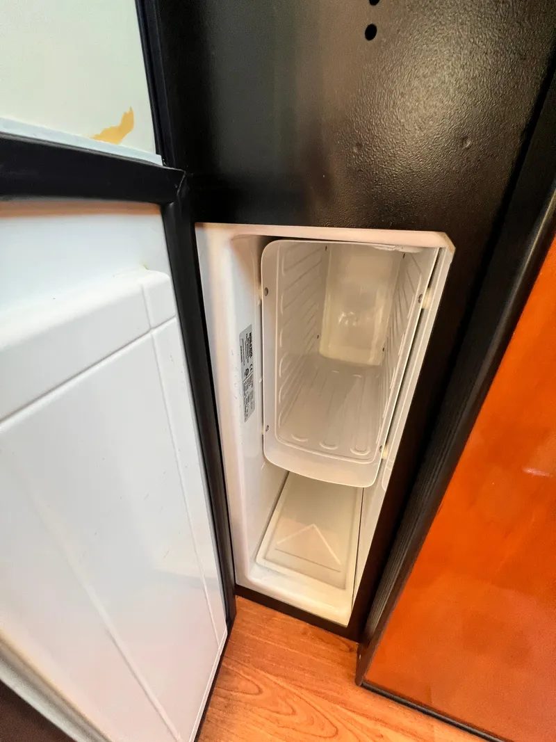 Slide: The Image of Open refrigerator door inside 2005 Carver 444 Cockpit Motor Yacht, showing empty freezer compartment. - 47