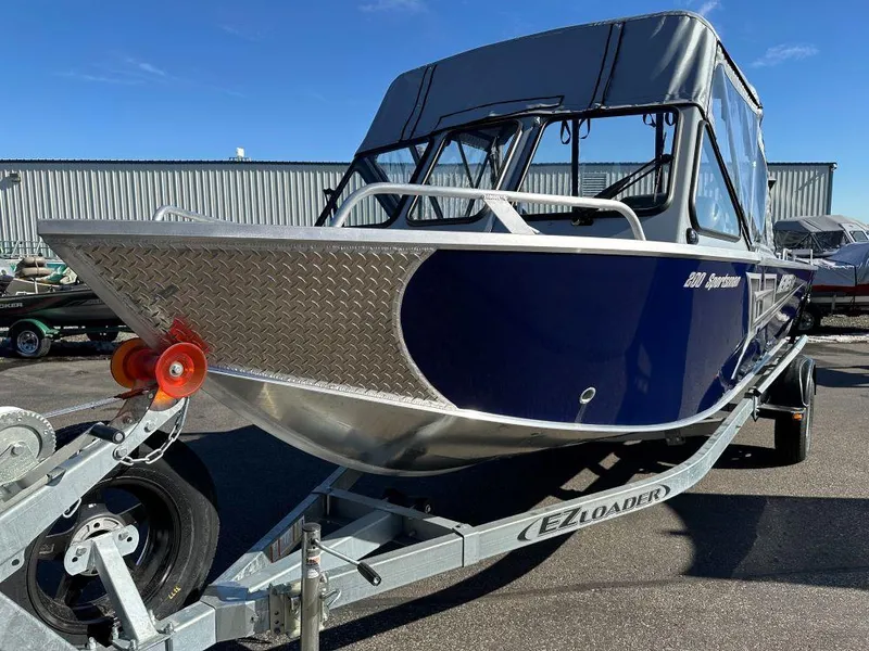 Slide: The Image of 2025 Hewescraft 200 Sportsman boat on EZ Loader trailer, parked outdoors. - 2