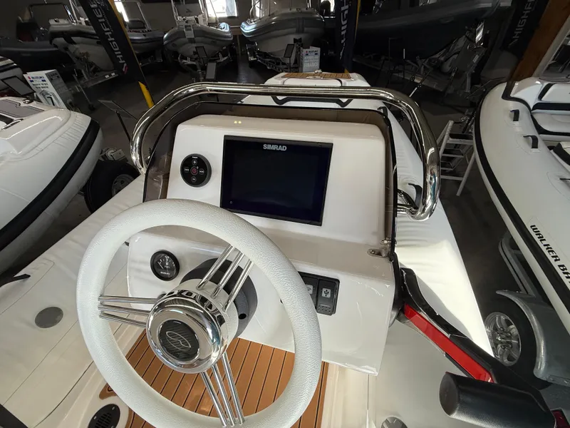 Slide: The Image of 2025 Walker Bay Generation 14 LTE boat dashboard with steering wheel and navigation display. - 2