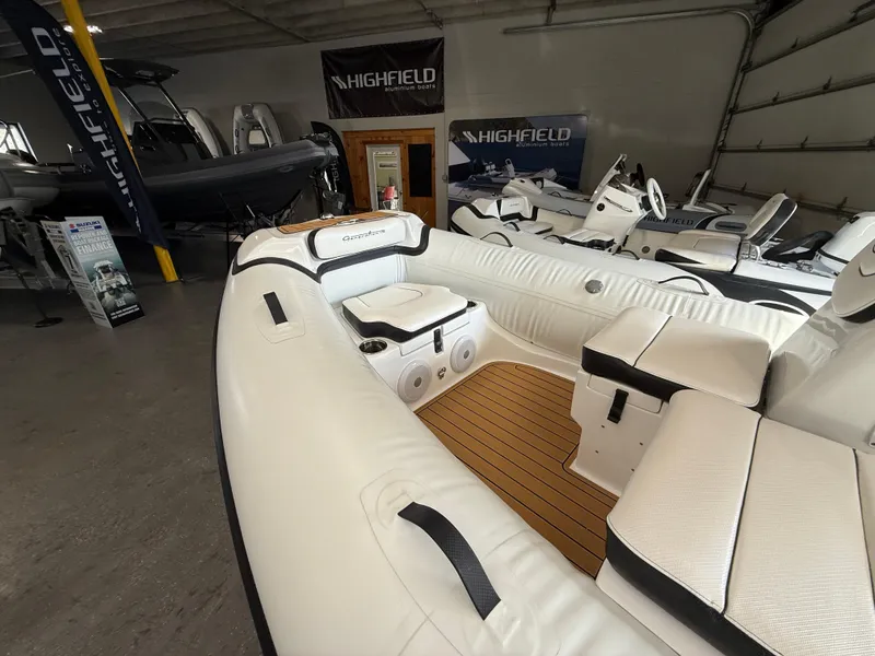 Slide: The Image of 2025 Walker Bay Generation 14 LTE inflatable boat in showroom, featuring white seating and wood accents. - 8
