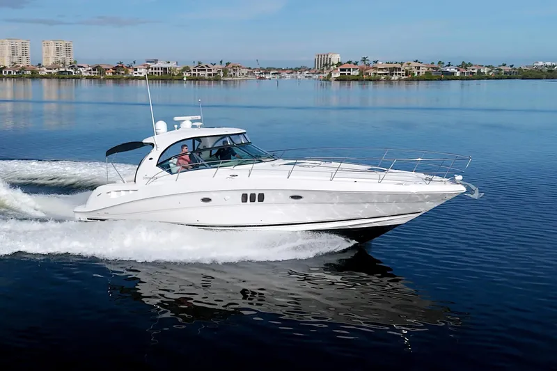 Slide: The Image of 2009 Sea Ray 44 Sundancer cruising on calm waters near a coastal city. - 4