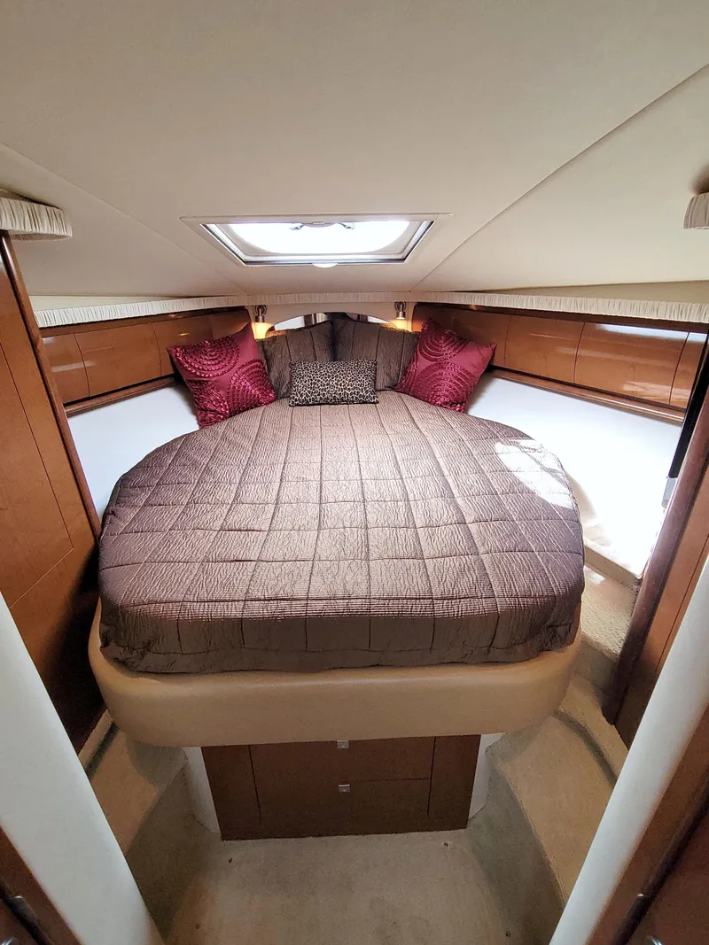 Slide: The Image of 2009 Sea Ray 44 Sundancer cabin with a cozy bed and elegant wood paneling. - 44