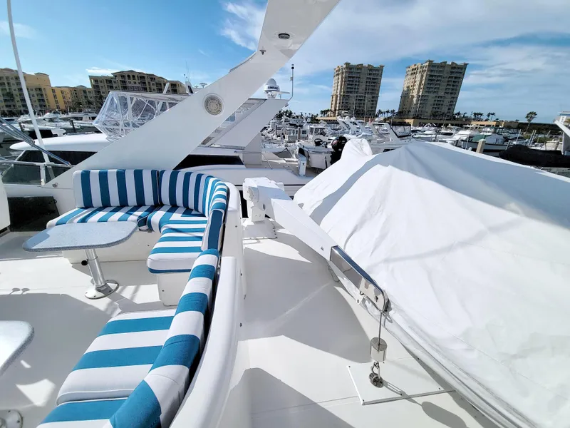 Slide: The Image of 1999 West Bay 58 Sonship yacht with striped seating, docked in a marina under a blue sky. - 22
