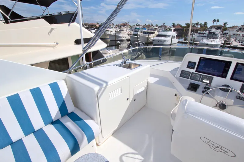 Slide: The Image of 1999 West Bay 58 Sonship yacht deck with striped seating and control panel in marina. - 25