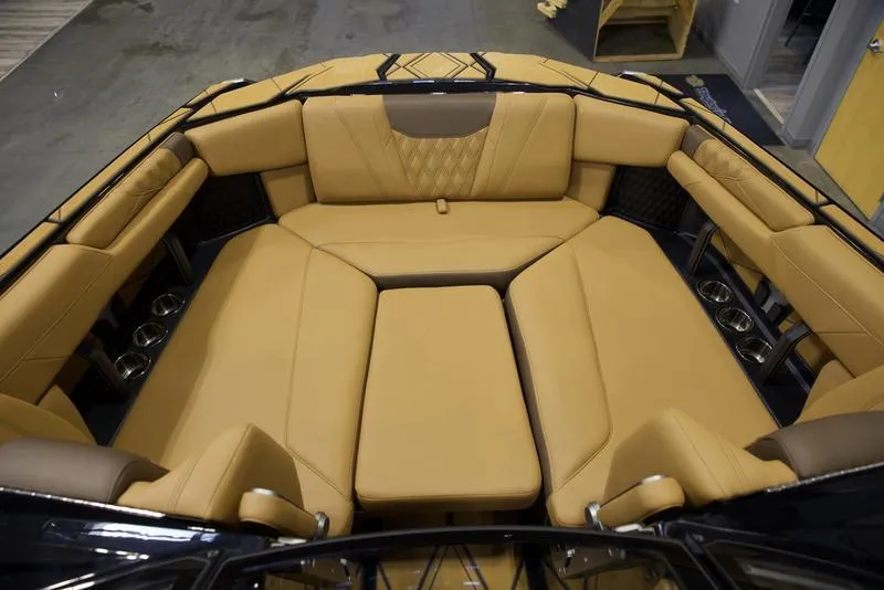 Slide: The Image of 2025 Malibu M242 boat interior with tan leather seating and cup holders. - 16