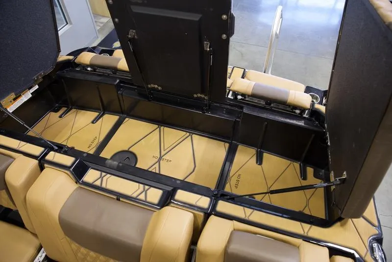 Slide: The Image of 2025 Malibu M242 boat interior storage compartment with tan upholstery and black framework. - 33