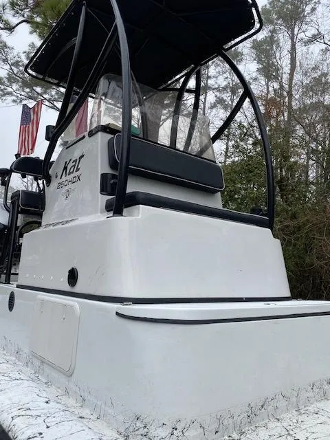 Slide: The Image of 2023 Dargel 250Kat HDX boat with T-top, white exterior, and American flags in the background. - 24