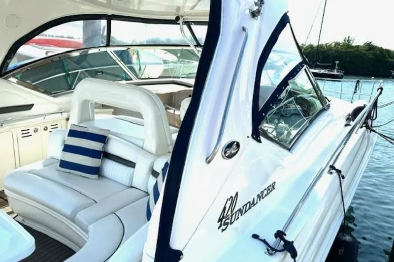 Slide: The Image of 2003 Sea Ray 420 Sundancer yacht interior with white seating and striped cushions at a marina. - 15