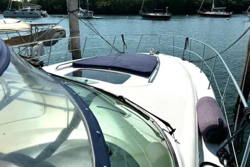 Slide: The Image of 2003 Sea Ray 420 Sundancer yacht docked at marina, featuring sleek design and clear canopy. - 28