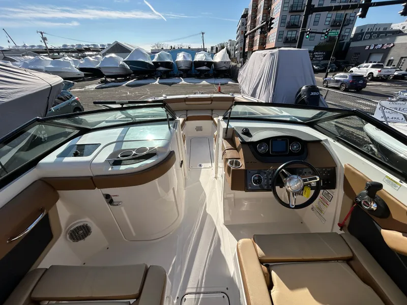 Slide: The Image of 2015 Sea Ray 270 Sundeck boat interior with steering wheel and seating, docked outdoors. - 5