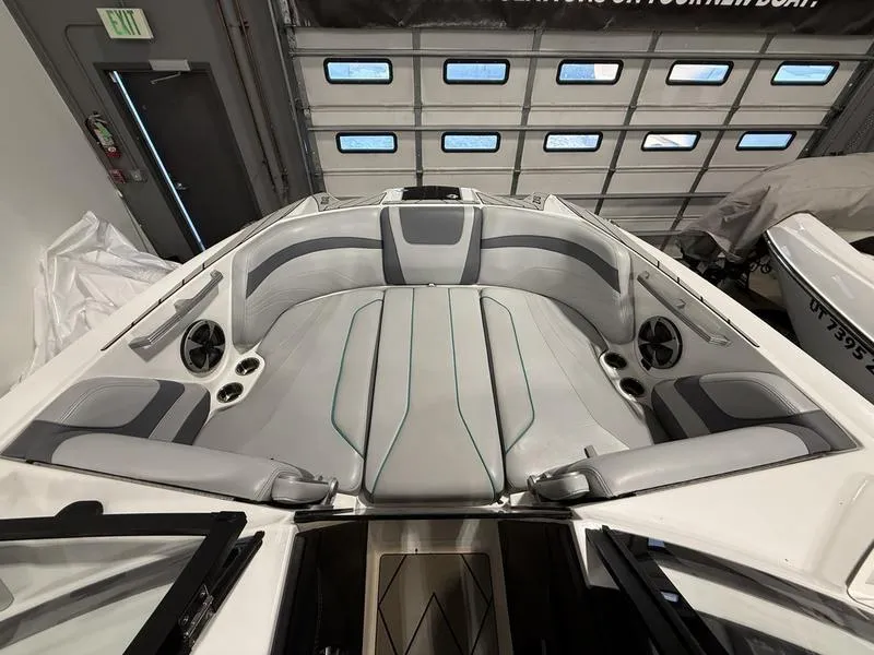 Slide: The Image of 2020 Malibu 24 MXZ boat interior with gray seating and built-in speakers. - 12