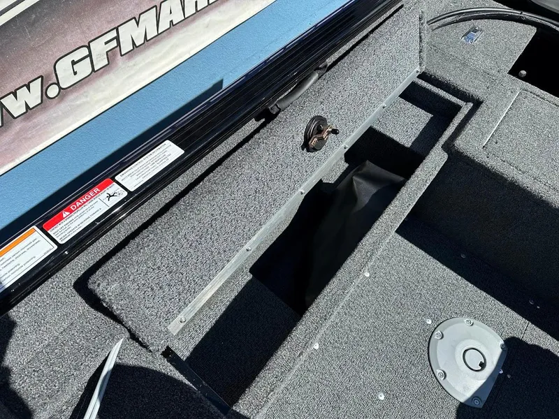 Slide: The Image of 2025 Lund 1650 Rebel XL SS boat interior with storage compartment and carpeted flooring. - 16