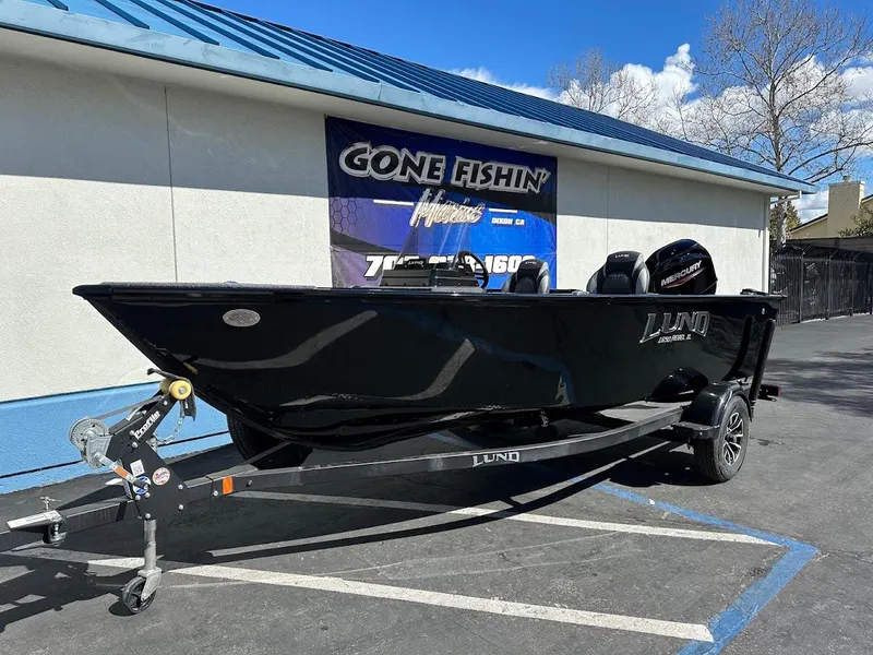 Slide: The Image of 2025 Lund 1650 Rebel XL SS boat on trailer, parked outside a building. - 2