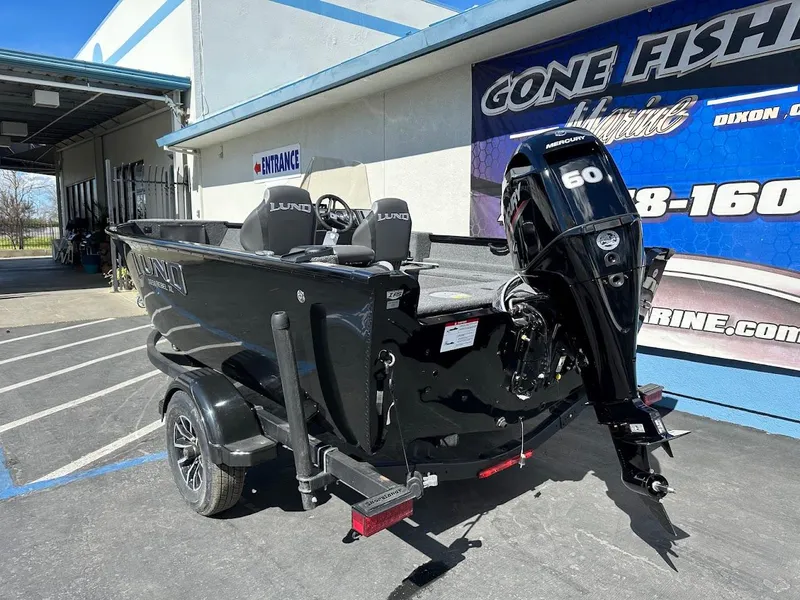 Slide: The Image of 2025 Lund 1650 Rebel XL SS boat with 60 HP engine, parked outside dealership. - 7