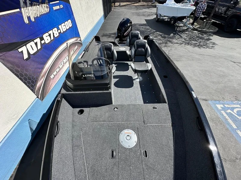 Slide: The Image of 2025 Lund 1650 Rebel XL SS boat, gray interior, parked outdoors near a dealership sign. - 9