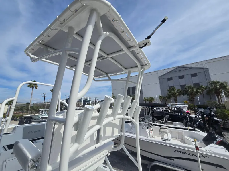 Slide: The Image of 2024 Shallow Sport X3 boat with T-top and rod holders, docked outdoors under a clear sky. - 12